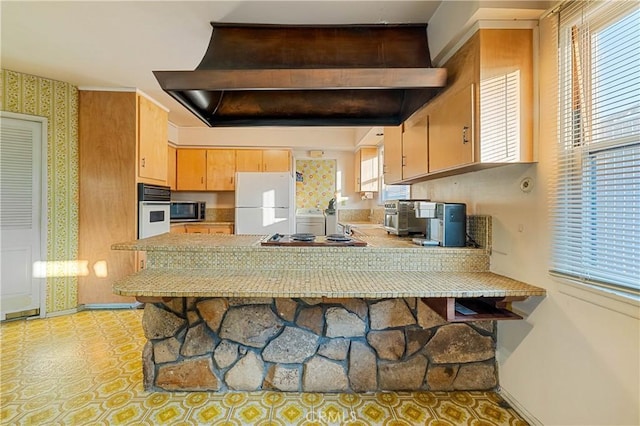 kitchen with custom range hood, white appliances, and kitchen peninsula