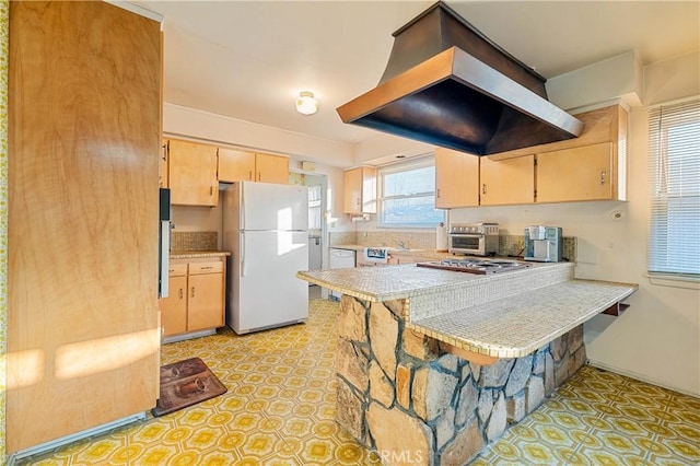 kitchen with white appliances, light brown cabinetry, range hood, and kitchen peninsula