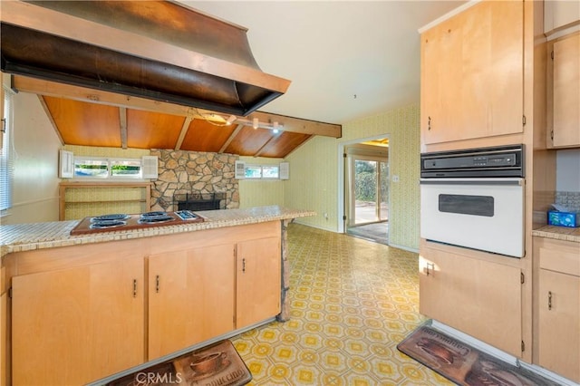 kitchen with white oven, lofted ceiling with beams, cooktop, exhaust hood, and light brown cabinets