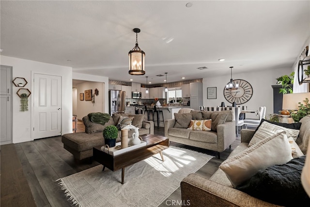 living room featuring an inviting chandelier and dark wood-type flooring