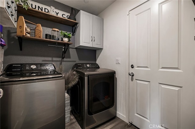 laundry room featuring dark wood-type flooring, cabinets, and washing machine and dryer