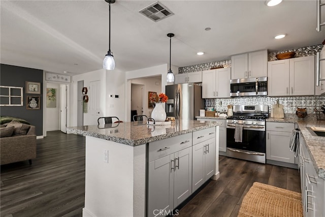 kitchen featuring pendant lighting, dark hardwood / wood-style flooring, stainless steel appliances, and a center island