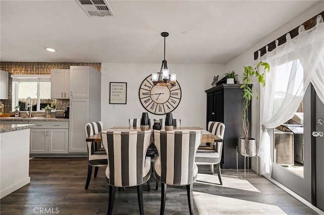 dining space with an inviting chandelier, dark hardwood / wood-style flooring, and sink