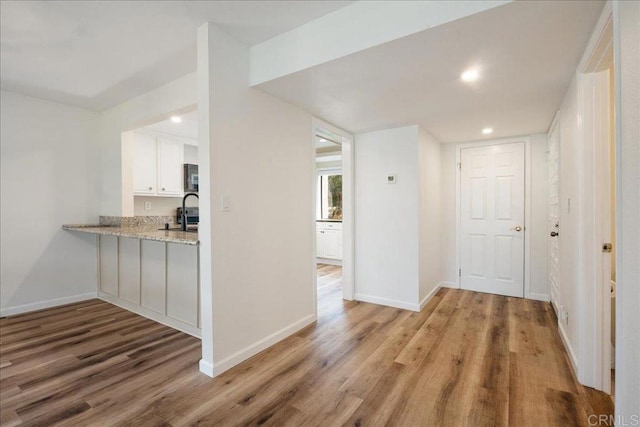 corridor featuring light wood finished floors, baseboards, and recessed lighting