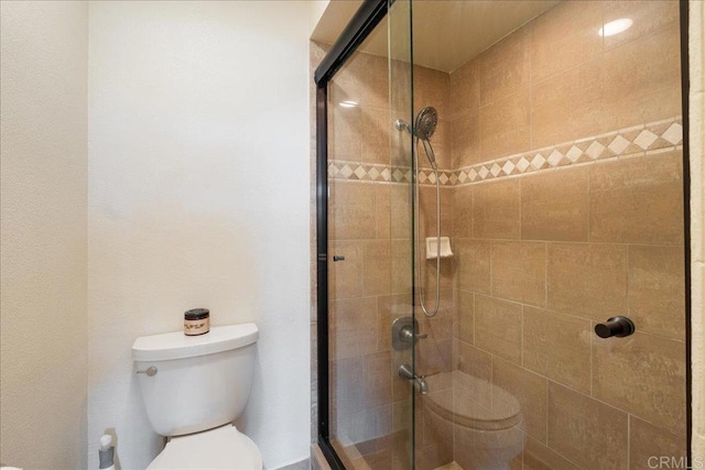 bathroom featuring toilet and a stall shower