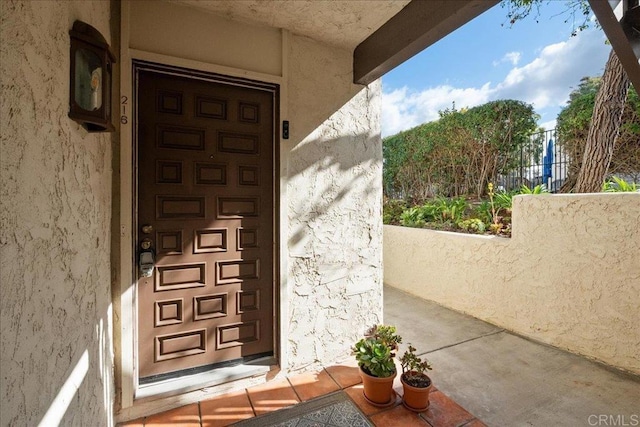 doorway to property featuring fence and stucco siding