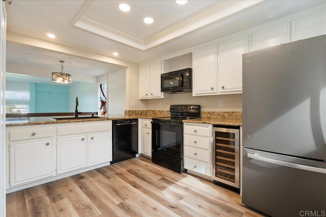 kitchen with wine cooler, a sink, white cabinetry, black appliances, and decorative light fixtures