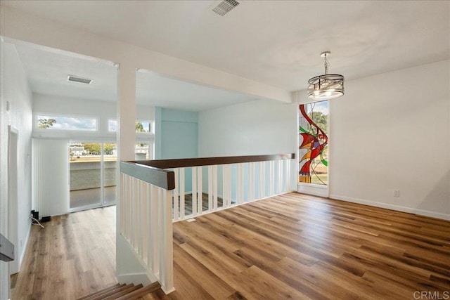 unfurnished room featuring visible vents, baseboards, wood finished floors, and beamed ceiling