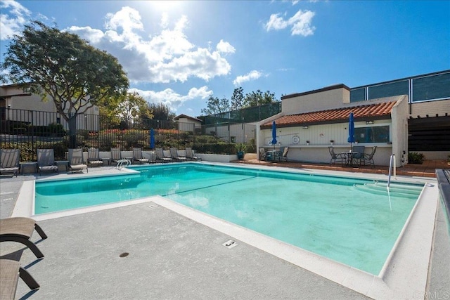 community pool with a patio area and fence