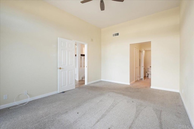 spare room with a ceiling fan, light colored carpet, visible vents, and baseboards