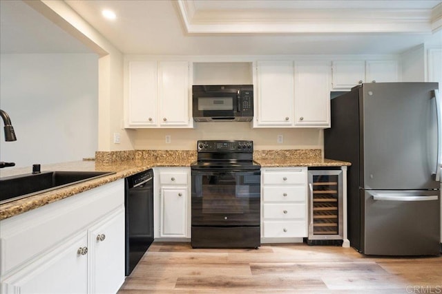 kitchen featuring wine cooler, a sink, white cabinets, light stone countertops, and black appliances