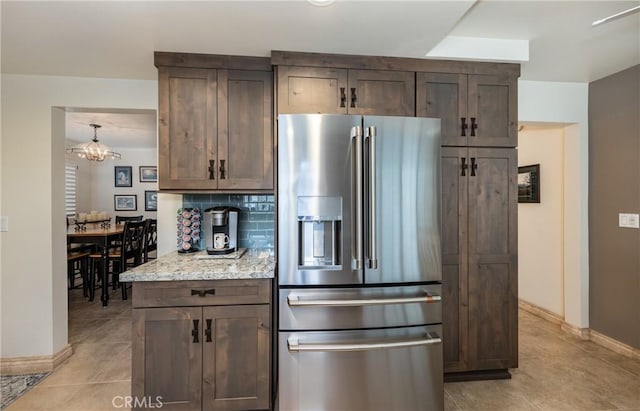 kitchen with light stone countertops, backsplash, high quality fridge, and light tile patterned flooring