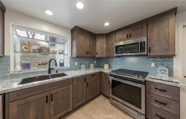 kitchen featuring sink, backsplash, light tile patterned floors, light stone counters, and stainless steel appliances