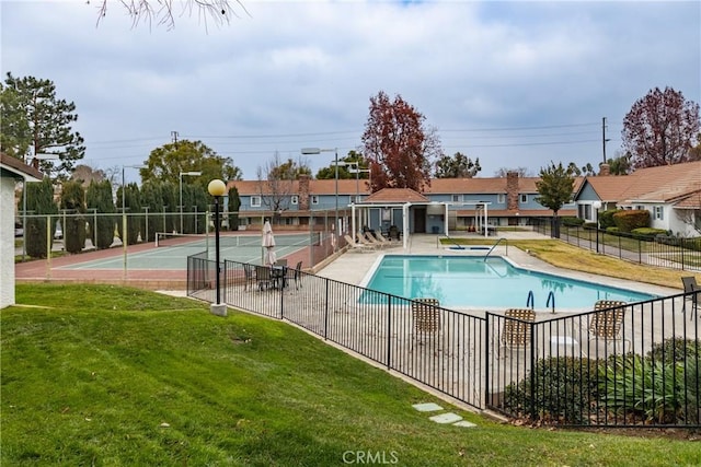 view of swimming pool featuring a yard and tennis court