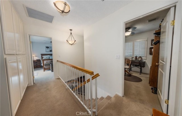 hall featuring light colored carpet and a textured ceiling