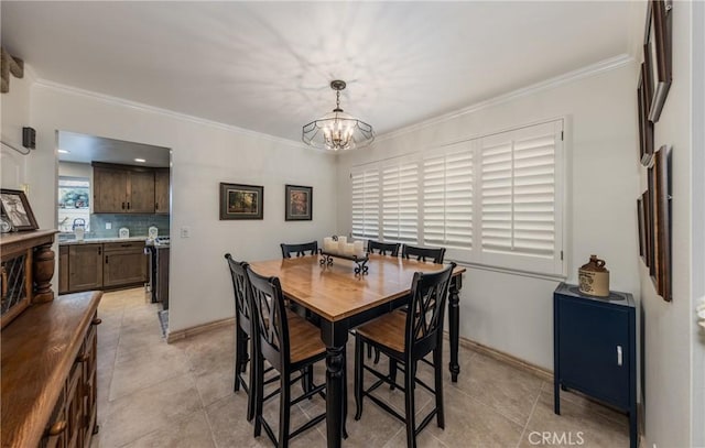 dining room with light tile patterned flooring, ornamental molding, and a chandelier