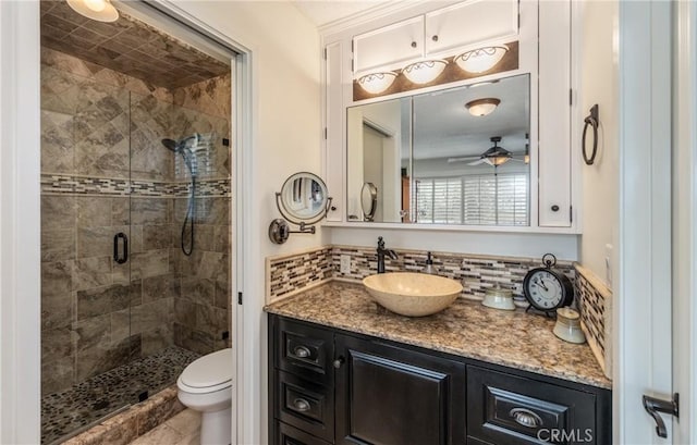 bathroom with vanity, backsplash, a shower with door, and toilet