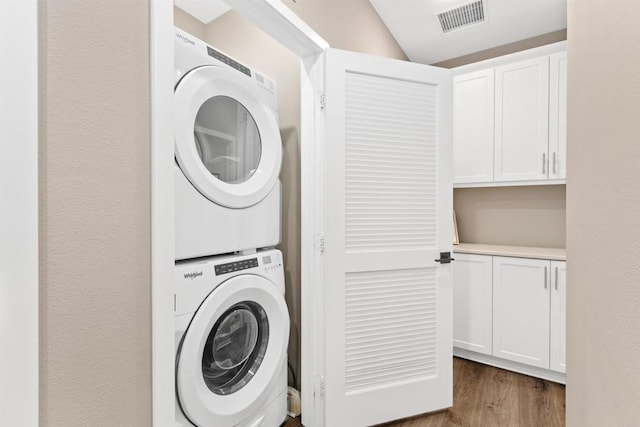 washroom featuring dark hardwood / wood-style floors and stacked washer / dryer