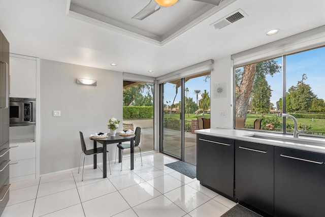 interior space with a healthy amount of sunlight, sink, stainless steel microwave, and white cabinets