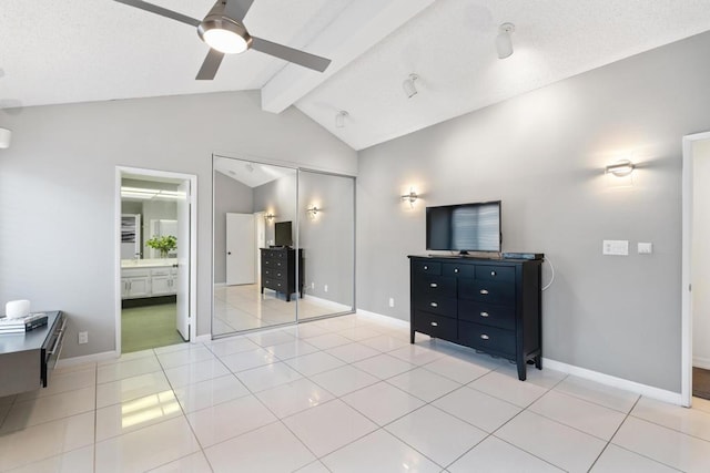 bedroom featuring vaulted ceiling with beams, ensuite bath, light tile patterned floors, a closet, and ceiling fan