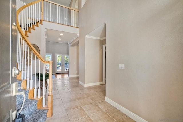 tiled foyer entrance with a high ceiling, ornamental molding, and french doors