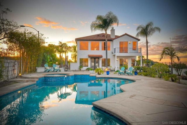 pool at dusk featuring an in ground hot tub and a patio area