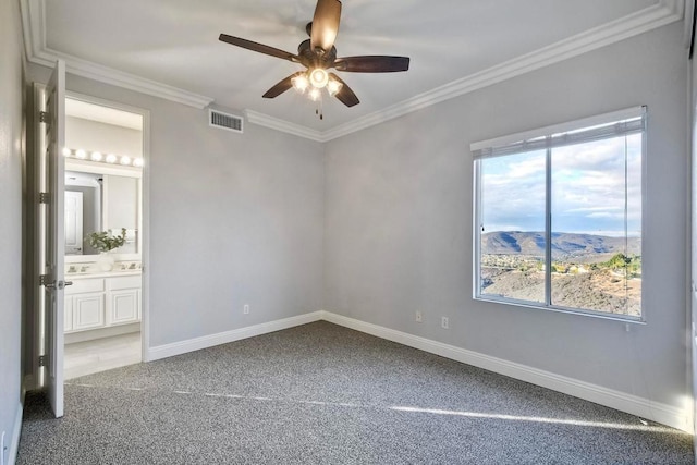 empty room with crown molding, a mountain view, carpet floors, and ceiling fan