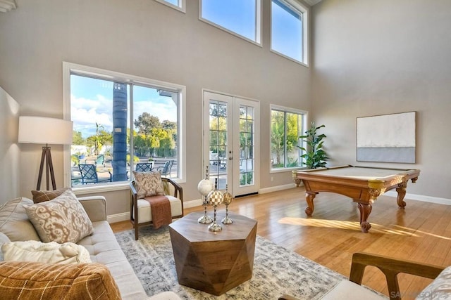 interior space featuring french doors, pool table, light hardwood / wood-style flooring, and a towering ceiling