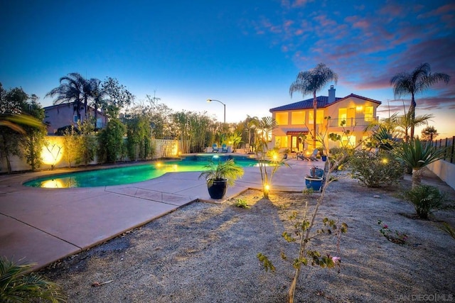 pool at dusk featuring a patio