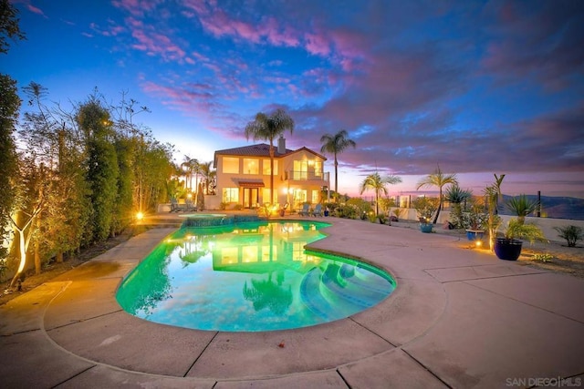 pool at dusk featuring a patio