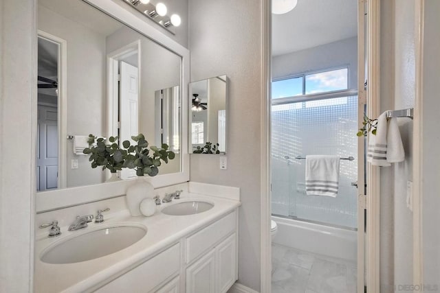 full bathroom with bath / shower combo with glass door, vanity, ceiling fan, and toilet