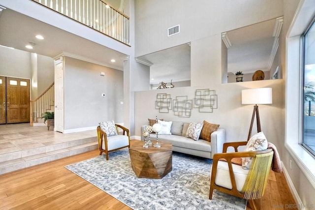 living room with a high ceiling, crown molding, and hardwood / wood-style floors