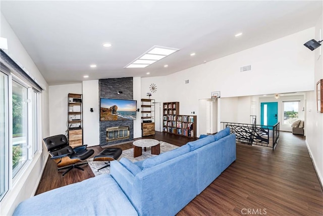 living room with plenty of natural light, a fireplace, dark hardwood / wood-style flooring, and vaulted ceiling with skylight