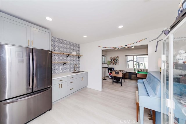 kitchen with light wood-type flooring, stainless steel fridge, sink, and white cabinets