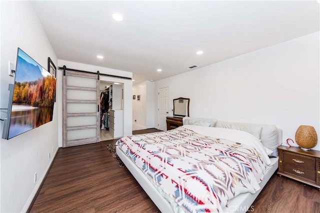 bedroom featuring dark hardwood / wood-style flooring, a closet, a spacious closet, and a barn door