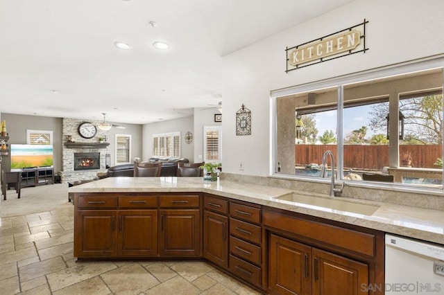 kitchen featuring a fireplace, white dishwasher, sink, and a wealth of natural light