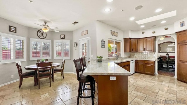 kitchen with sink, a breakfast bar, ceiling fan, backsplash, and kitchen peninsula