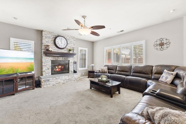 carpeted living room with ceiling fan and a fireplace