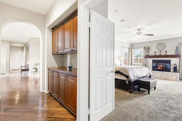 bedroom with ornamental molding, dark wood-type flooring, ceiling fan, and a fireplace