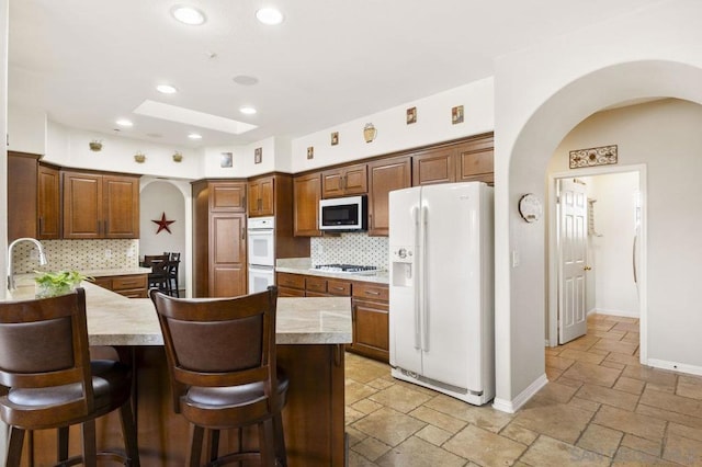 kitchen featuring sink, a skylight, appliances with stainless steel finishes, a kitchen breakfast bar, and decorative backsplash