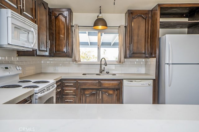 kitchen featuring decorative light fixtures, sink, backsplash, dark brown cabinets, and white appliances