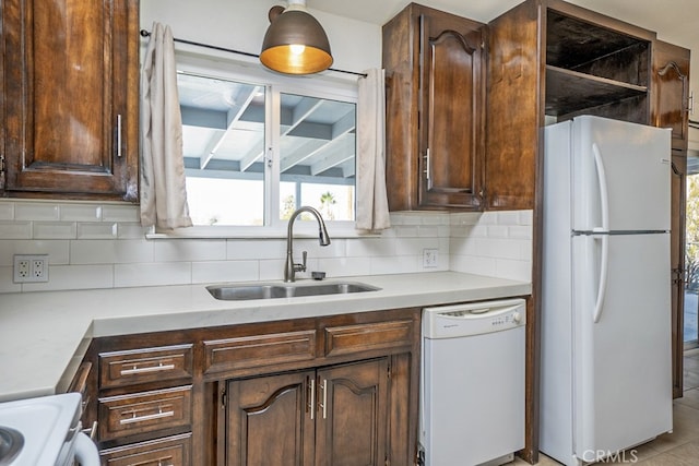 kitchen featuring pendant lighting, tasteful backsplash, sink, dark brown cabinets, and white appliances