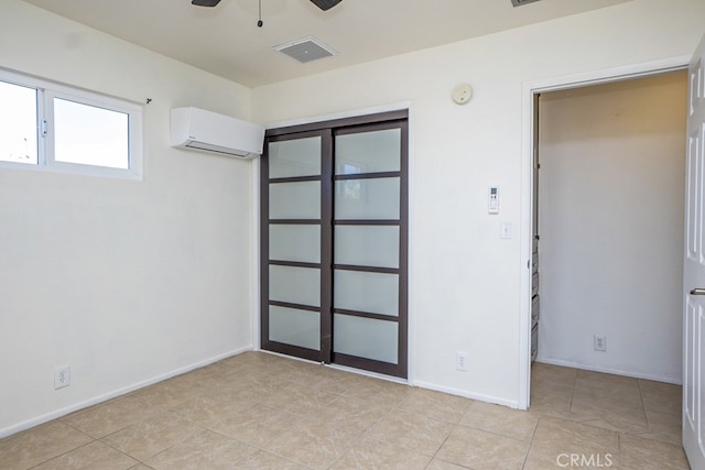 spare room with a wall mounted air conditioner, ceiling fan, and light tile patterned floors