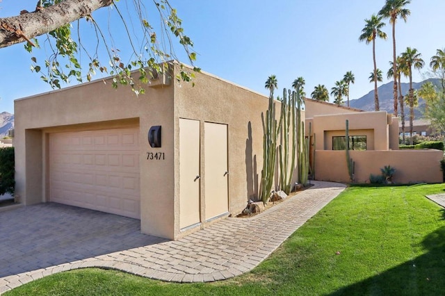 exterior space featuring a garage, a mountain view, and a front lawn