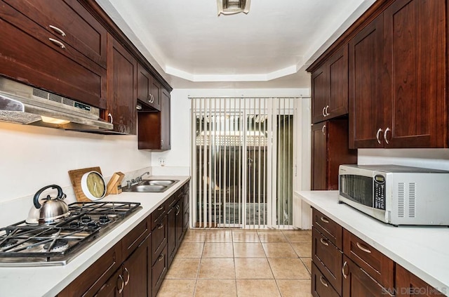 kitchen featuring light tile patterned flooring, a raised ceiling, sink, dark brown cabinetry, and stainless steel appliances