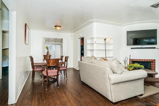 living room featuring a tile fireplace and dark wood-type flooring