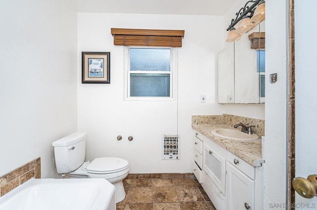 bathroom featuring vanity, heating unit, a bathing tub, and toilet