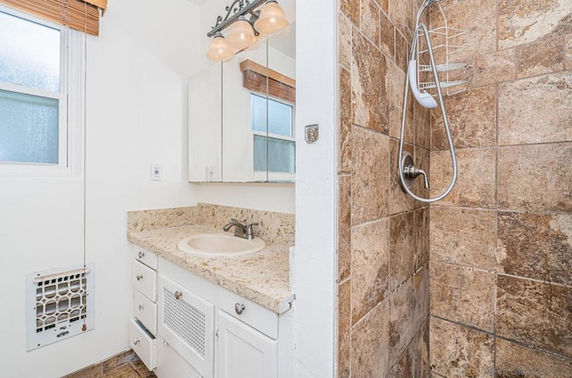 bathroom with tiled shower and vanity