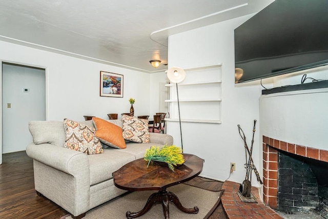 living room featuring a brick fireplace and dark wood-type flooring