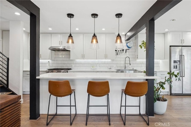 kitchen with pendant lighting, high quality fridge, sink, and white cabinets